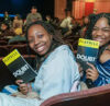 Students smile and hold Playbills during a Roundabout Theatre Company Student Matinee Series performance.
